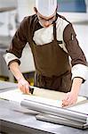 Baker slicing dough in kitchen