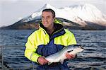 Worker holding salmon by rural lake