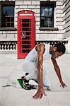 Olympic sprinter on starting line with red telephone box in background