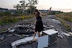 Teenage girl standing on pile of rubbish