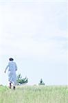 Young woman walking in field, rear view