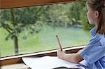 School girl holding a pencil and staring out of a classroom window