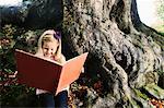 Young girl reading a book in a woodland