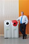 Businessman disposing of bottle in recycling bin, portrait