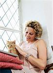 Mid adult woman stroking cat and using laptop