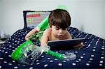Boy lying on bed with snorkeling gear, using digital tablet