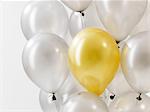 Golden balloon in silver balloons against white background