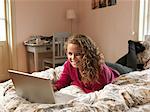 Young woman using laptop on bed