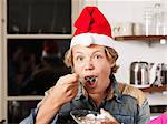 Portrait of teenage boy wearing Santa hat eating cake