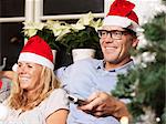 Mature couple wearing Santa hats on sofa