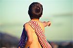 Boy pointing into distance with striped fabric on shoulder