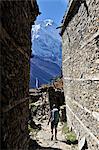 Woman treks through medieval stone buildings, Ghyaru, Nepal