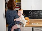 Mother holding baby daughter in kitchen