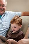 Boy looking at digital tablet with grandfather