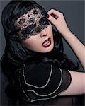 Portrait of young woman with black lace covering eyes