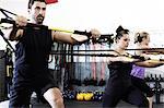 People working out in gym with exercise bar and resistance cord