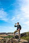 Male hiker on rock, drinking water
