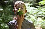 Boy with eyes closed smelling leaf