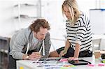 Colleagues discussing photographs on desk in creative office