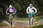 Two female mountain bikers riding through water