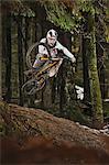 Mountain biker jumping muddy forest track