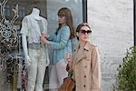 Woman dressing mannequin in shop window