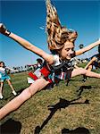 Young cheerleaders performing routine on football field