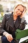 Mature woman wearing leather jacket and smiling in park, portrait