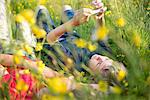 Boys lying in long grass playing on smartphone