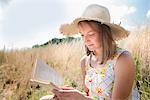 Adolescent girl sitting in sun reading story book