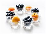 Still life with circle of apricots and blueberries in glass tumblers