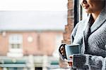 Young woman in kitchen holding mug of coffee