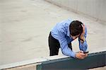 Anxious young man leaning on wall on city rooftop