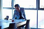 Mature businesswoman at conference table checking papers