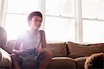 Boy using game controller  from living room sofa