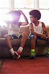 Two brothers with game controllers sitting on living room sofa
