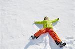 Young boy making snow angel in snow