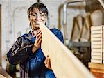 Woman examining straightness of wood plank in printing workshop