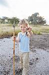 Portrait of young boy holding spear and scorpion, Otavi, Etosha, Namibia