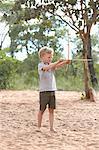 Young boy on sand holding home-made bow and arrow