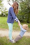 Teenage girl with toddler brother standing on her feet in garden