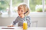 Young boy sitting at table holding pen, thinking