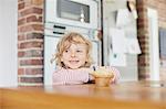 Young boy standing by kitchen counter,with muffin on counter in front of him