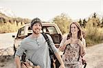 Young couple preparing to go hiking, carrying firewood, smiling