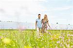 Young couple walking through field next to solar farm