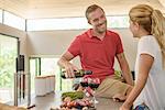 Couple preparing food and pouring red wine in kitchen