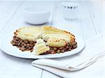 Still life of cottage pie with minced beef, gravy and vegetables on white plate