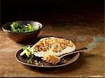 Still life of Orkney crab gratin in crab shell with bowl of mixed salad and lime