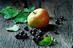 Cox's apples and blackcurrants on old wooden surface