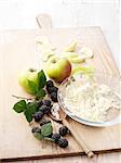 Ingredients for apple and blackberry crumble on whitewashed wooden table